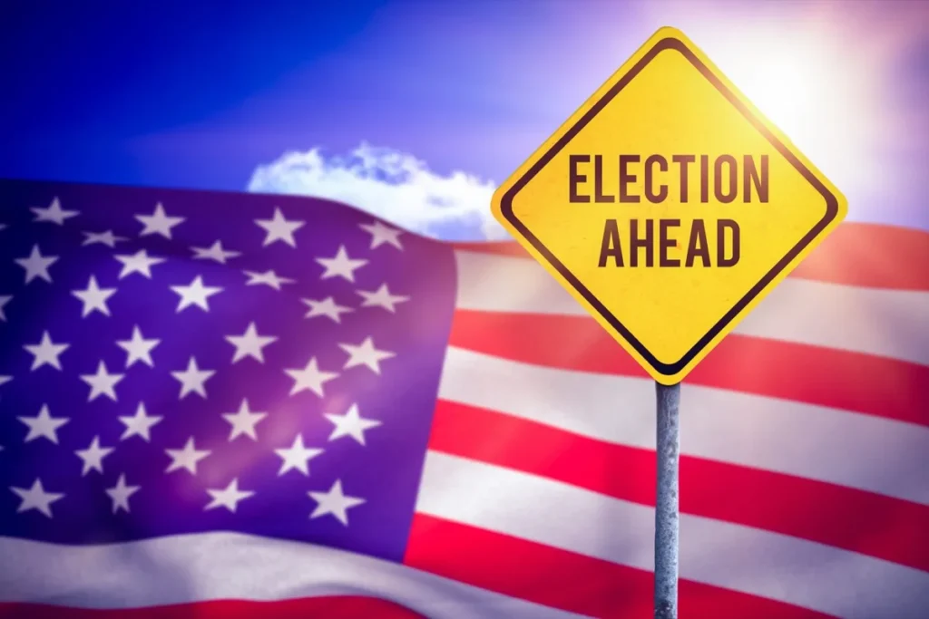Yellow diamond road sign reading Election Ahead in front of an American flag